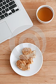 Laptop computer with japanese fished shaped cake and tea