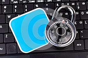 Laptop computer keyboard, a number code combination padlock and a blank empty square label, cybersecurity, account security