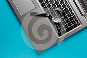 Laptop computer with magnifying glass on blue background, concept of search. Internet security conceptual image