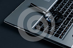 Laptop computer with magnifying glass on dark background, concept of search. Internet security