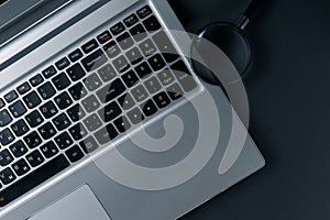 Laptop computer with magnifying glass on dark background, concept of search. Internet security conceptual image