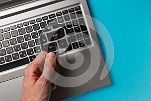 Laptop computer and man`s hand with magnifying glass on blue background, concept of search