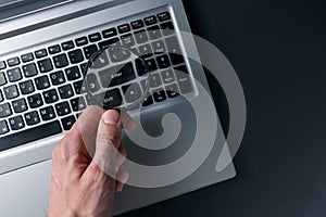 Laptop computer and man`s hand with magnifying glass on dark background, concept of search. Internet security conceptual image.