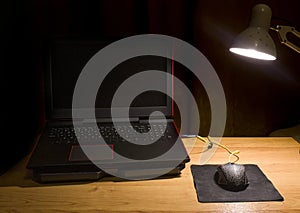 Laptop with a computer mouse on the table under the light of a desk lamp. Workplace at home and at work.