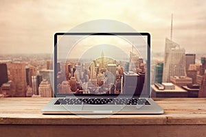 Laptop computer over New York city skyline. Retro filter effect