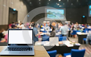 Laptop computer seminar room in attendee background.