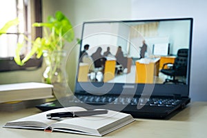 Laptop computer showing chroma green screen on LCD display stands on a desk with books next to ready for further design and copy