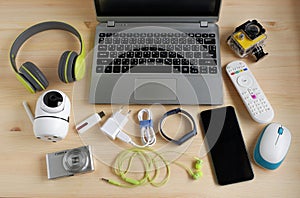 Laptop computer with smartphone and camera and other electronic gadgets on wooden background.Top view