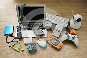 Laptop computer with Smartphone and portable game consoles and ebook reader and many electronic gadgets on wooden background