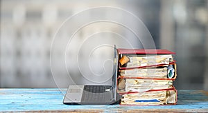 Laptop computer and stack of messy ringbinders with grungy business paperwork, bureaucracy,beat the clock,heavy workload concept