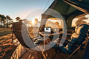 A laptop computer and two tourist chairs in a tent on campsite.