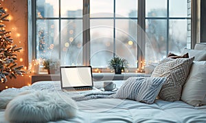 Laptop computer on white bed sheets in cozy modern hotel room with copy space blank screen and sunrise city view on the background