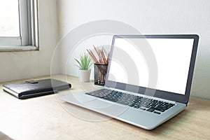 Laptop computer with white blank screen on wood desk. Workspace, workplace, desktop office concept