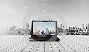 Laptop computer on wood floor with modern city view