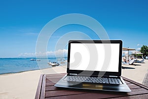 Laptop computer on wood table at the beach in summer