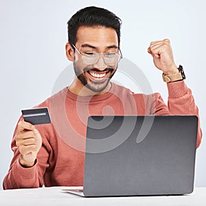 Laptop, credit card and man excited for online shopping, e commerce and payment in studio. Asian male person with
