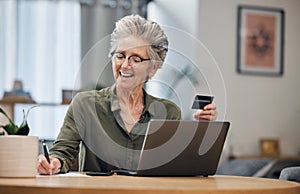 Laptop, credit card and senior woman paying her bills, debt or mortgage with online banking. Elderly lady planning a