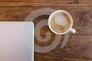 A laptop and a cup of coffee over a wood table