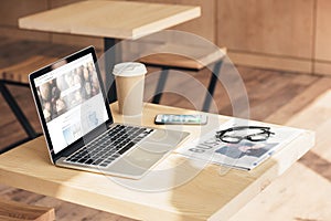 laptop with depositphotos, smartphone and business newspaper on table