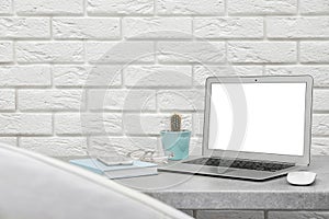 Laptop on desk against brick wall in home office