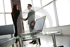 Laptop on the desk, background handshake