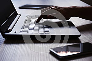 Laptop, digital tablet, smart phone, a male hand using laptop with mobile computing devices on the office desk