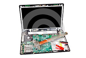 Laptop disassembled with hammer and screwdrivers on it