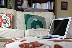 Laptop on a fabric top with couch on sight, a home environment. Work from home of flexi work concept photo
