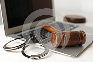 Laptop, gavel and handcuffs on white table. Cyber crime