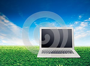 Laptop on grass with sky background