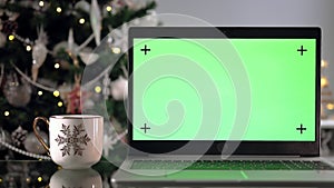 Laptop with green screen next to the Christmas tree