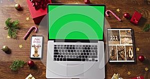 Laptop with green screen on screen, with smartphone,tablet and christmas decorations