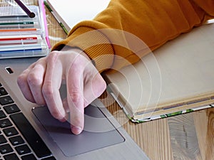 A laptop with hand and a study book.