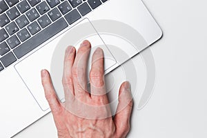Laptop and hand, top view. The user works on a modern laptop using a trackpad. Modern technology