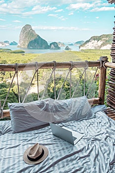 Laptop and hat against Phang Nga bay background, Tourists relaxing in tropical resort at Samet Nang She, near Phuket in Southern