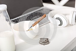 laptop, headphones, police badge and bowl with breakfast