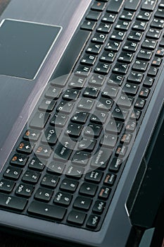 Laptop, keyboard close-up on a dark wooden table, copy space, vertical format