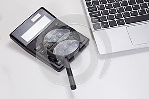 Laptop keyboard, magnifying glass and calculator
