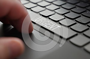 On the laptop keyboard of a person& x27;s hand, on the space bar there is an inscription - Urgent