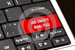 On the laptop keyboard the red button written Job Safety Analysis