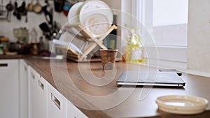 Laptop lied on a kitchen table with kitchenware in the background