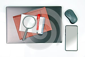 Laptop, magnifying glass, computer mouse, smartphone, pen, notepad on a white background. Items for business and buying goods