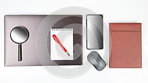 Laptop, magnifying glass, computer mouse, smartphone, pen, notepad on a white background. Items for business and buying goods