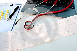Laptop, medical device for listening stethoscope, Notepad, ecg paper on white background, medical research, insurance and