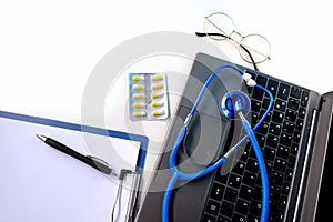 Laptop, medical device for listening stethoscope, Notepad, pills, capsules on white background, medical research, insurance and