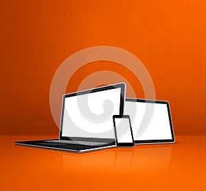 Laptop, mobile phone and digital tablet pc on orange office desk