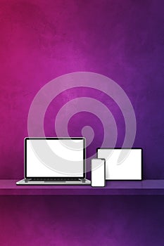 Laptop, mobile phone and digital tablet pc on purple wall shelf. Vertical background