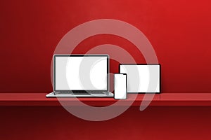 Laptop, mobile phone and digital tablet pc on red wall shelf. Horizontal background