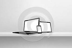 Laptop, mobile phone and digital tablet pc on white concrete wall shelf. Horizontal background