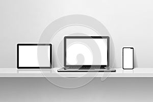 Laptop, mobile phone and digital tablet pc on white concrete wall shelf. Horizontal background